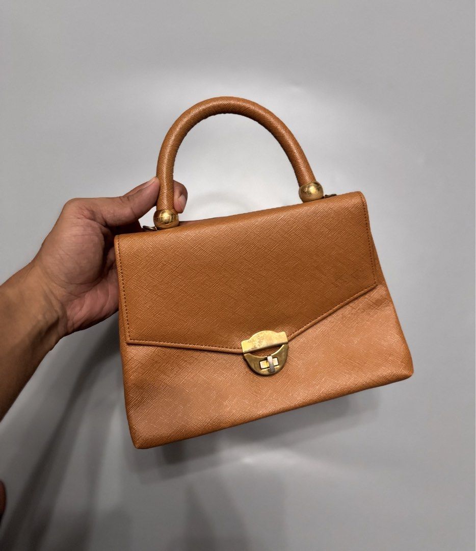 Vintage Tan Structured Top Handle Handbag Gold Hardware (Category: Luxury Bags & Wallets) located in Alaminos. Submitted by outfitcheck.ph (Listing ID 1467485254, Image 1). Description: - Color: Classic Tan - Material: Pebbled saffiano-style texture - Hardware: Elegant gold-tone metal balls - Closure: Secure front flap turn-lock - Interior: Smooth cream-lined flap - Size: Compact, ideal for daily essentials - Condition: Clean stitching throughout