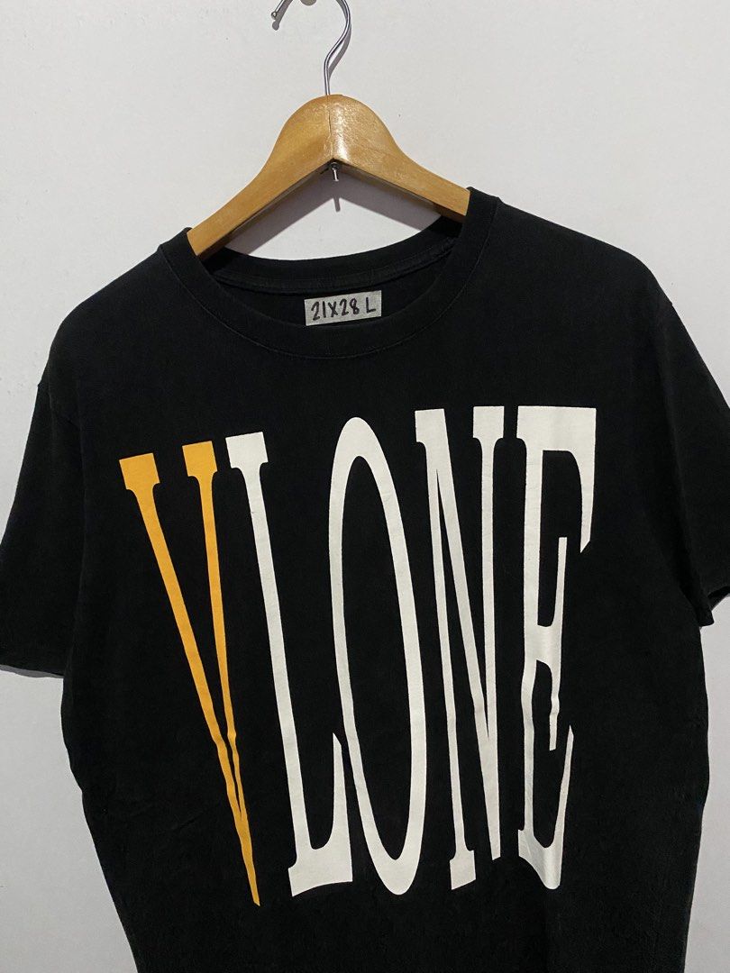 Vlone Black Tee With Yellow V Logo (Category: Tshirts & Polo Shirts ) located in Jaen. Submitted by oshimamark58418 (Listing ID 1467552431, Image 3). Description: Black Vlone t-shirt. Large yellow V graphic on the back. Front has Vlone text print in white and yellow. Tag says size M, but handwritten tape shows 21x28 L. 100% cotton material. Made in China..