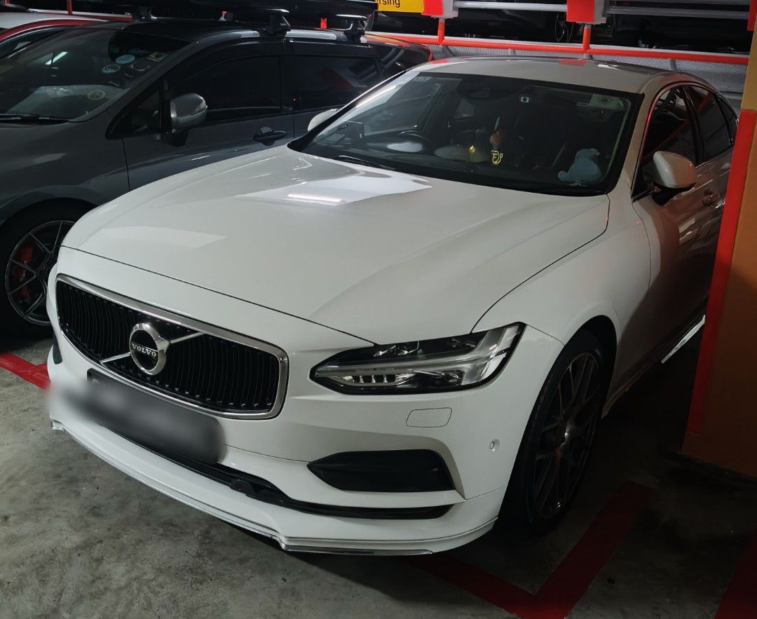 Volvo S90 T5 Momentum (A) (Category: Used Cars) located in Singapore. Submitted by arvin53.ks (Listing ID 1467540149, Image 2). Description: White Volvo S90 sedan parked indoors. Right-hand drive layout with black leather interior upholstery and multi-spoke alloy wheels. Centre touchscreen infotainment display, digital instrument cluster, and textured floor mats installed. Clean bodywork and well-maintained cabin space..
