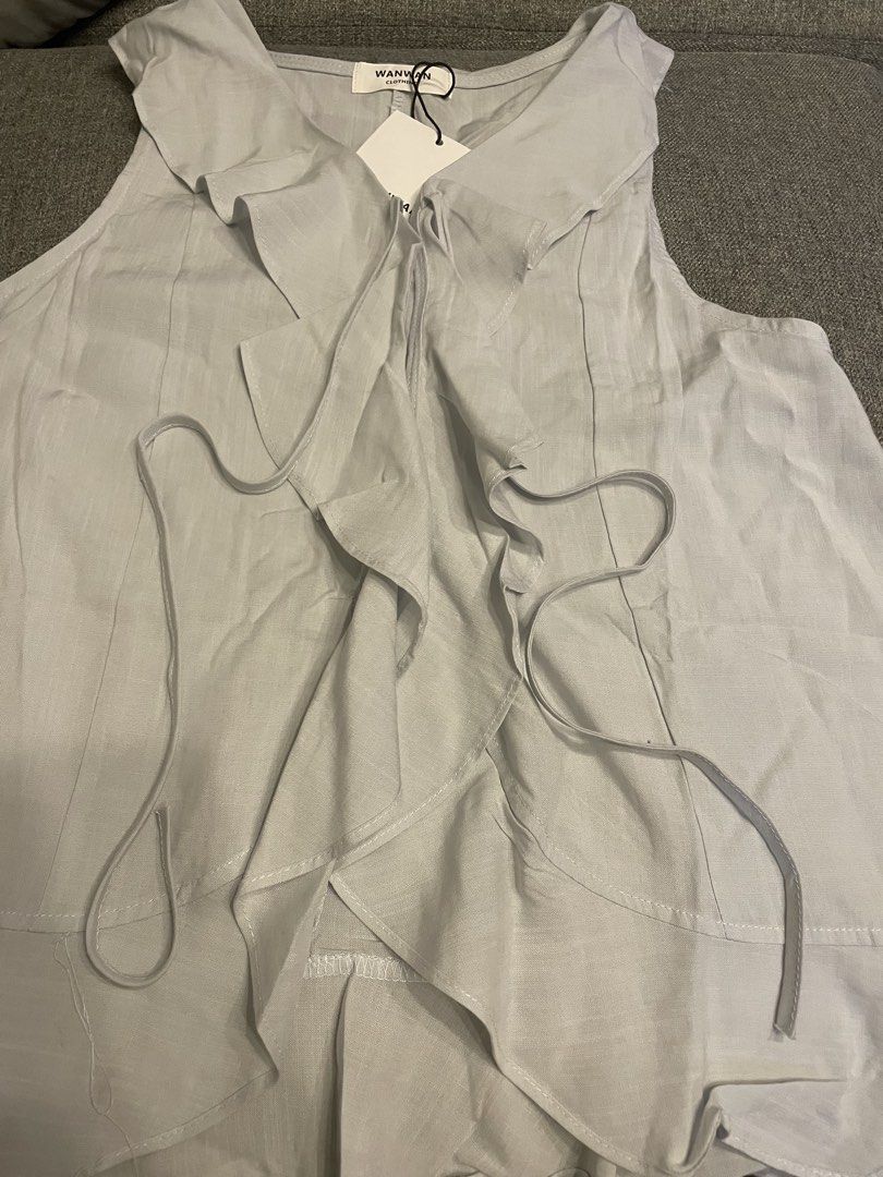 Wanwan BKK Ruffle Sleeveless Top (Category: Blouses) located in Quezon City. Submitted by mfordma (Listing ID 1467371389, Image 2). Description: BRAND NEW Originally bought for 650.00 Doing a little closet decluttering! ✨ Letting go of some pieces that are still in great condition and looking for a new home. 🤍 Brand: Wanwan Clothing Size: Free size Color: Light Gray Description: - Cotton lightweight sleeveless top with a flared bottom hem - Ruff