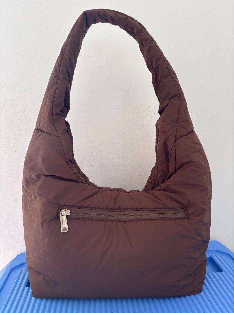 Westbronco Puffer Shoulder Bag Brown (Category: Shoulder Bags) located in Pasig City. Submitted by pammyyyy.11 (Listing ID 1467538698, Image 2). Description: - Brand/Model: Westbronco Puffer Shoulder Bag - Color: Brown - Material: Soft quilted fabric - Design: Comfortable curved strap with a cute matching flower charm - Storage: Convenient zip pocket on the back side - Condition: Clean interior and exterior, ready to wear.