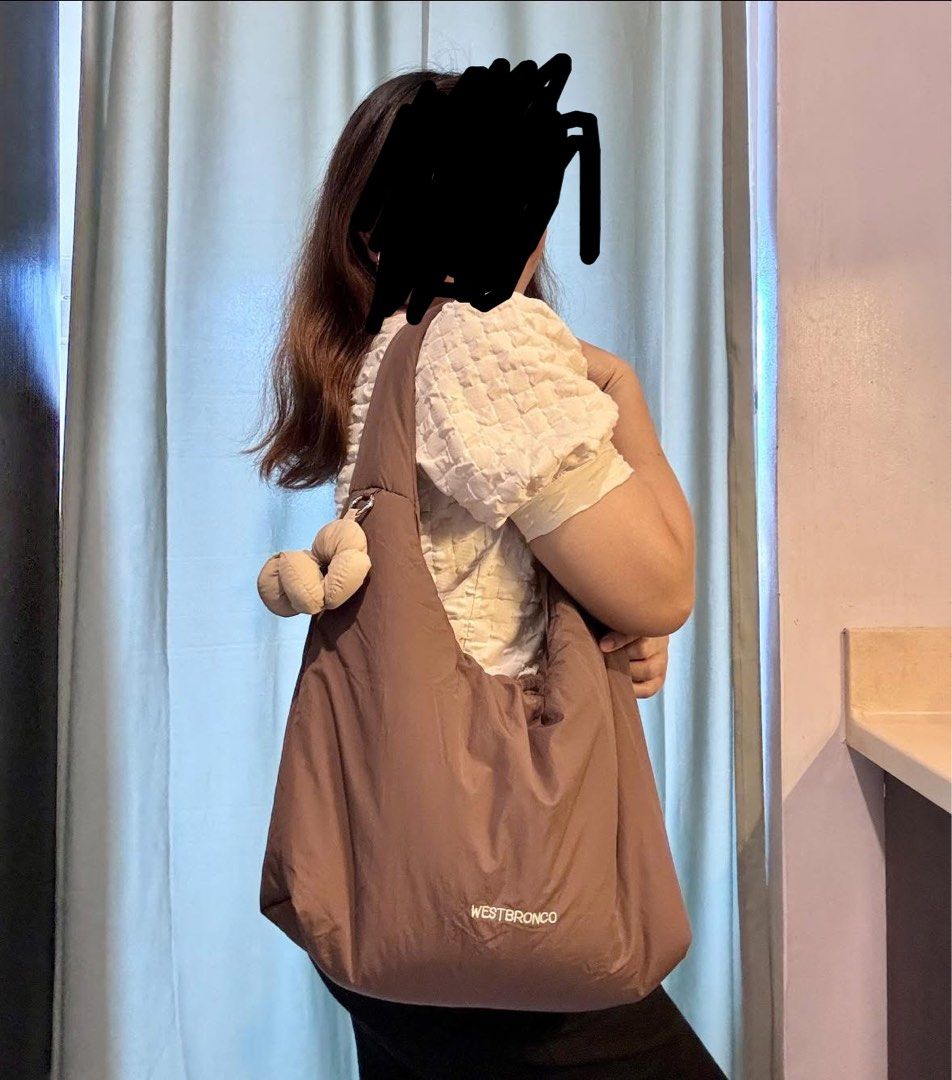 Westbronco Puffer Shoulder Bag Brown (Category: Shoulder Bags) located in Pasig City. Submitted by pammyyyy.11 (Listing ID 1467538698, Image 3). Description: - Brand/Model: Westbronco Puffer Shoulder Bag - Color: Brown - Material: Soft quilted fabric - Design: Comfortable curved strap with a cute matching flower charm - Storage: Convenient zip pocket on the back side - Condition: Clean interior and exterior, ready to wear.