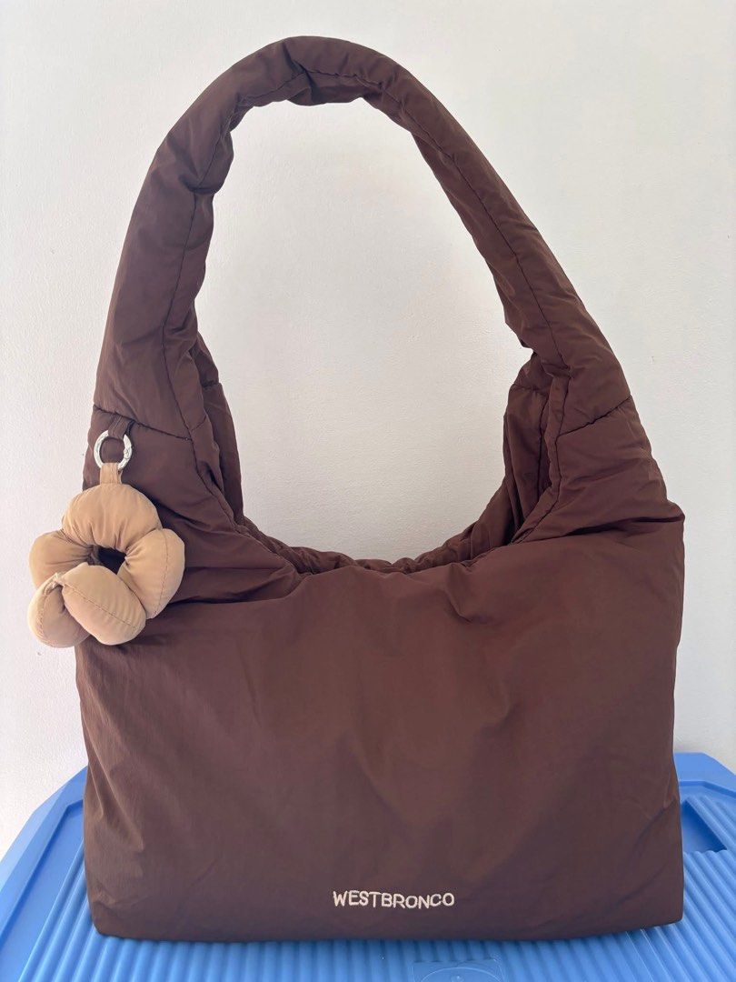 Westbronco Puffer Shoulder Bag Brown (Category: Shoulder Bags) located in Pasig City. Submitted by pammyyyy.11 (Listing ID 1467538698, Image 1). Description: - Brand/Model: Westbronco Puffer Shoulder Bag - Color: Brown - Material: Soft quilted fabric - Design: Comfortable curved strap with a cute matching flower charm - Storage: Convenient zip pocket on the back side - Condition: Clean interior and exterior, ready to wear.