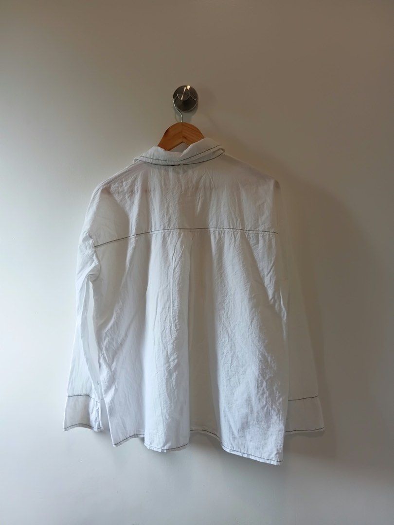 White button-up shirt with contrast stitching size M-L (Category: Shirts) located in Antipolo. Submitted by wisecat.4a7eea (Listing ID 1467402598, Image 2). Description: - Color: Classic White - Fit: Medium to Large - Material: Lightweight and breathable fabric - Design: Contrast stitching on pockets and seams with contrasting black buttons - Storage: Two functional chest pockets - Styling: Perfect to pair with jeans or trousers.
