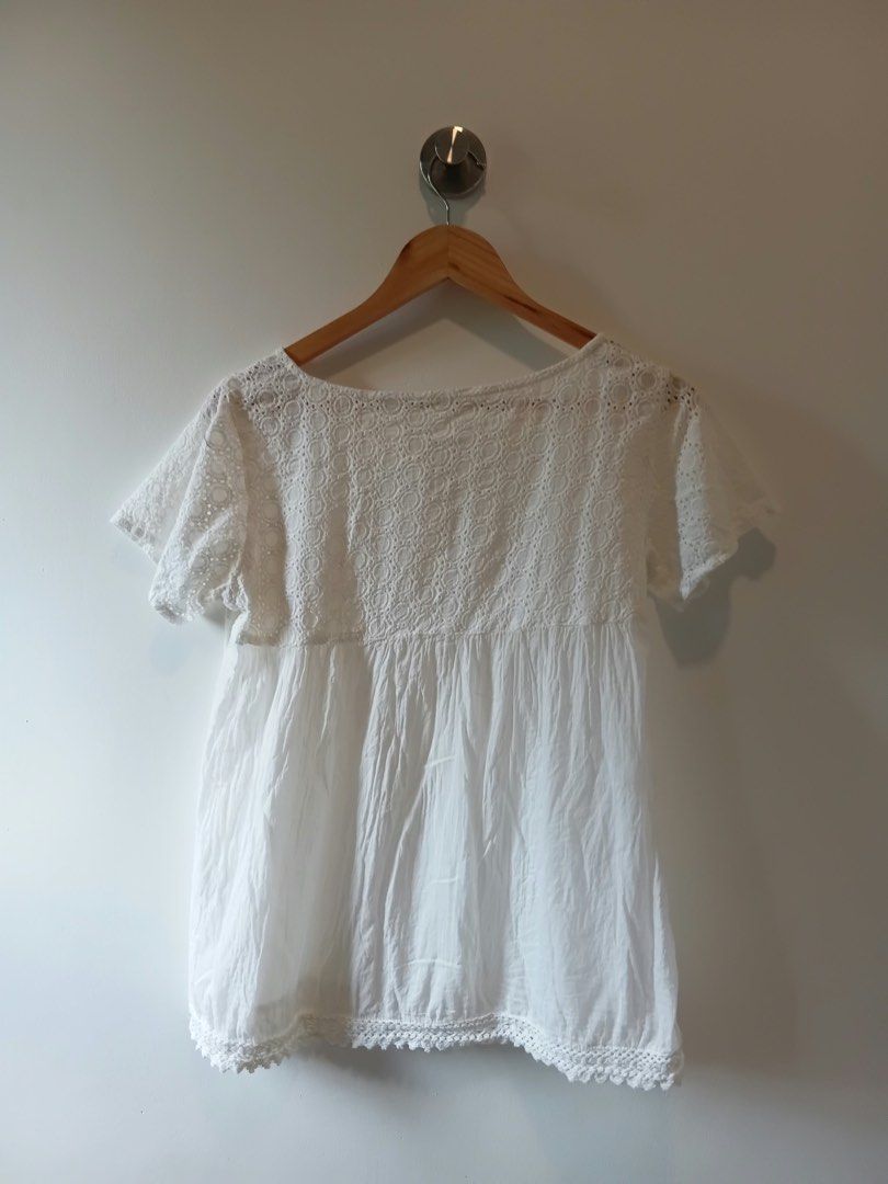 White lace trim button-up blouse top S-M (Category: Blouses) located in Antipolo. Submitted by wisecat.4a7eea (Listing ID 1467401246, Image 2). Description: - Color: White - Fit: Comfortably fits Small to Medium - Material: Lightweight gathered fabric - Design: Cut-out lace yoke and sleeves, front button closure - Details: Matching buttons and crocheted lace trim along the bottom hem - Styling: Great basic piece for warm weather, easy to pair wit