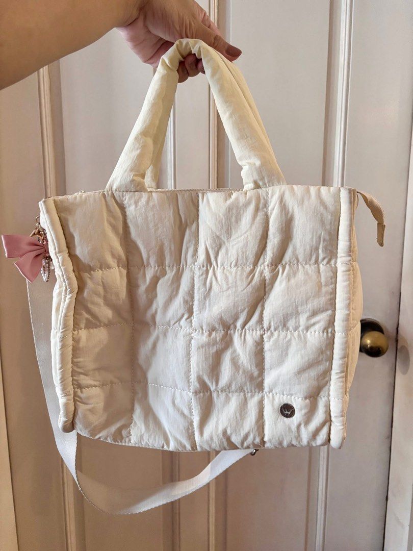 White Quilted Tote Bag with Crossbody Strap (Category: Tote Bags) located in Pasig City. Submitted by pammyyyy.11 (Listing ID 1467543233, Image 1). Description: - Style: White quilted puffer tote bag - Closure: Secure top zip closure - Straps: Dual top handles and an adjustable long strap for versatile wear - Details: Small circular logo patch near the bottom corner - Capacity: Roomy interior that easily fits your daily essentials - Versatility: 