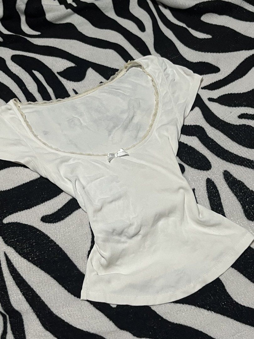 White Ribbed Scoop Neck Tee With Lace Trim (Category: Shirts) located in Manila. Submitted by y2kcloset_ (Listing ID 1467477220, Image 2). Description: - Color/Design: White ribbed short-sleeve top with delicate cream lace trim and a front satin bow - Fit: Body-hugging, fitted silhouette - Material: Super soft and comfortable ribbed cotton, perfect for daily wear - Styling: Easy to pair with jeans, shorts, or skirts - Condition: Brand new / Excel