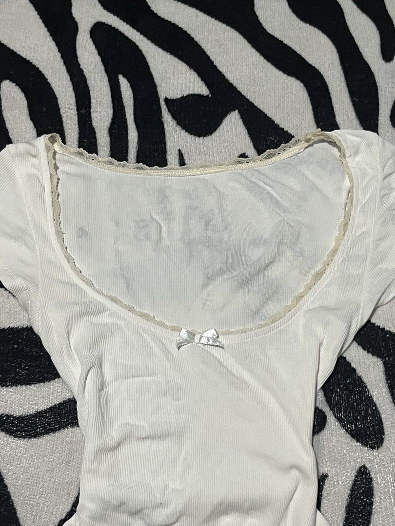 White Ribbed Scoop Neck Tee With Lace Trim (Category: Shirts) located in Manila. Submitted by y2kcloset_ (Listing ID 1467477220, Image 3). Description: - Color/Design: White ribbed short-sleeve top with delicate cream lace trim and a front satin bow - Fit: Body-hugging, fitted silhouette - Material: Super soft and comfortable ribbed cotton, perfect for daily wear - Styling: Easy to pair with jeans, shorts, or skirts - Condition: Brand new / Excel