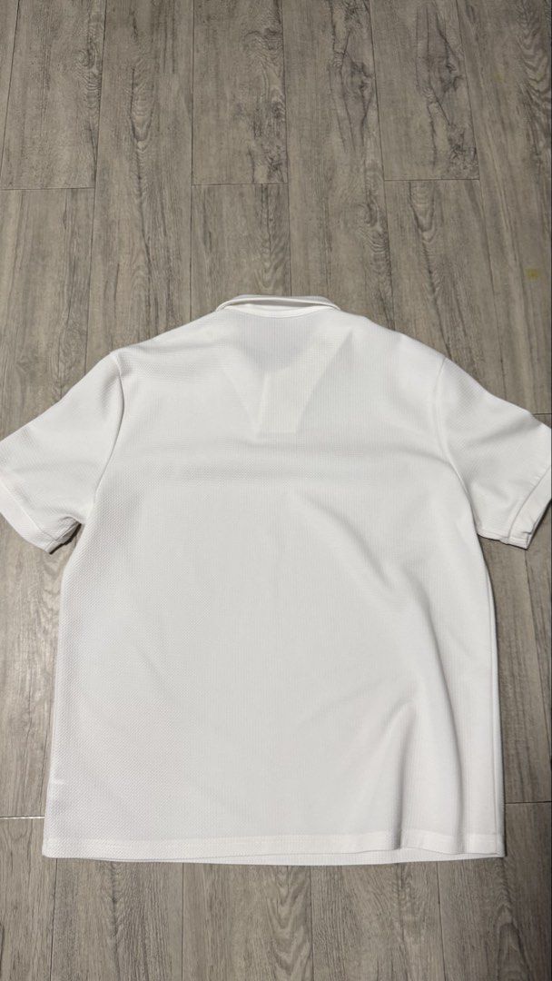 White Short Sleeve Polo Shirt (Category: Tshirts & Polo Shirts ) located in Quezon City. Submitted by kobeeeee_12 (Listing ID 1467513817, Image 2). Description: - Color: White - Style: Minimalist streetwear - Design: Textured knit pattern with a spread collar and open placket - Fit: Relaxed fit through the body - Fabric: Breathable, ideal for warm weather.
