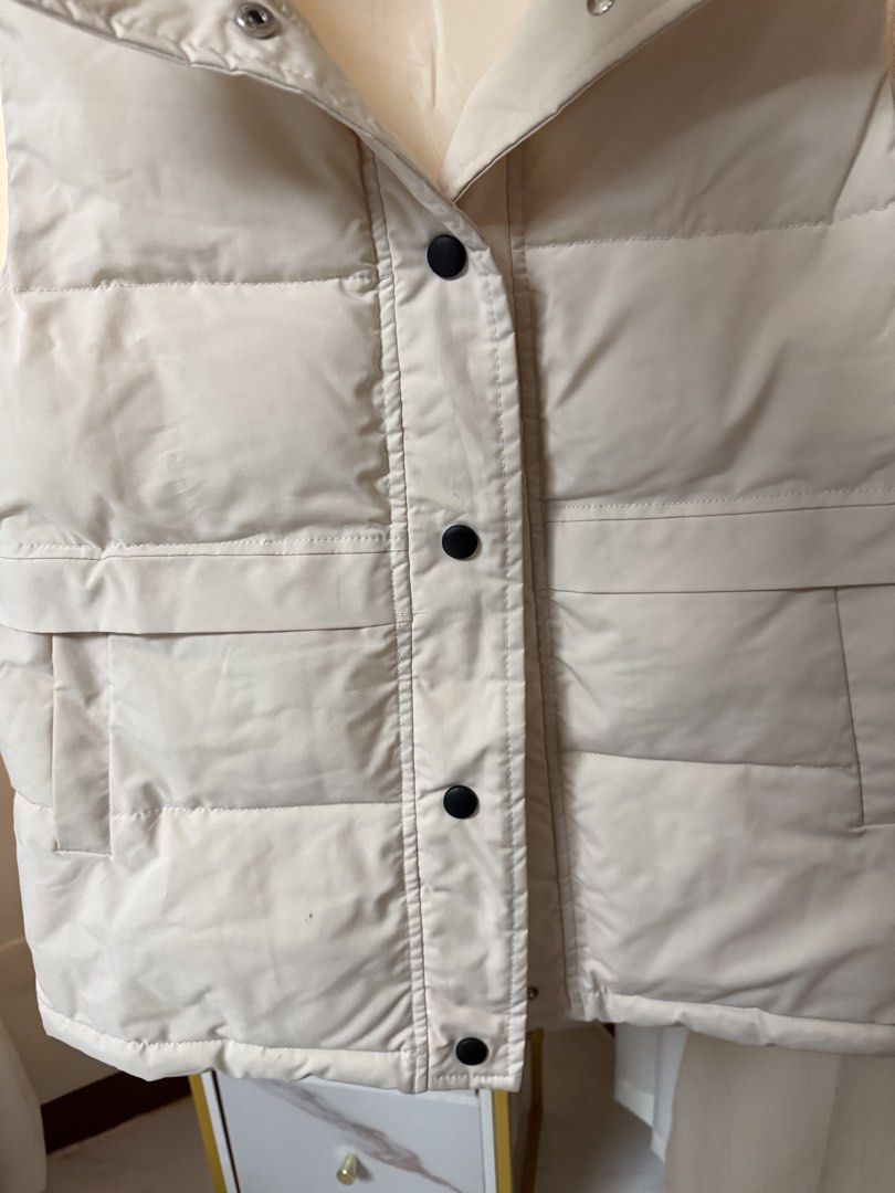 Winter Cream Puffer Vest With Snap Buttons (Category: Sleeveless) located in Cavite. Submitted by galoreforsale (Listing ID 1467376599, Image 2). Description: - Color: Cream / Neutral - Style: Sleeveless puffer vest with high neck collar - Closure: Front dark snap buttons - Pockets: Two deep front pockets - Design: Padded horizontal quilt - Best for: Easy layering in cooler weather.