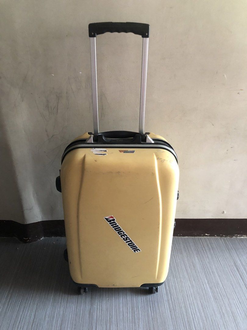 Yellow hard shell rolling suitcase with handle (Category: Luggage) located in Cavite. Submitted by ai__chang (Listing ID 1467408239, Image 1). Description: - Type: Yellow hard shell suitcase - Security: Built-in side combination lock - Interior: Patterned fabric lining, zippered mesh divider pocket, and adjustable compression straps - Condition: Fully functional zipper closure, minor exterior scuffs, and a Bridgestone sticker on the front.