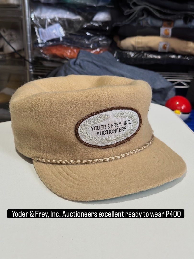 Yoder & Frey Inc. Auctioneers Wool Cap (Category: Caps & Hats) located in Daet. Submitted by thrifthings2018 (Listing ID 1467446471, Image 1). Description: - Color: Tan wool with a green underbrim - Design: Structured crown, flat brim, and braided cord trim - Patch: Embroidered Yoder & Frey, Inc. Auctioneers logo on the front - Comfort: Dri-N-Cool interior sweatband - Fit: Adjustable strap closure with gold-tone hardware - Condition: Clean and re