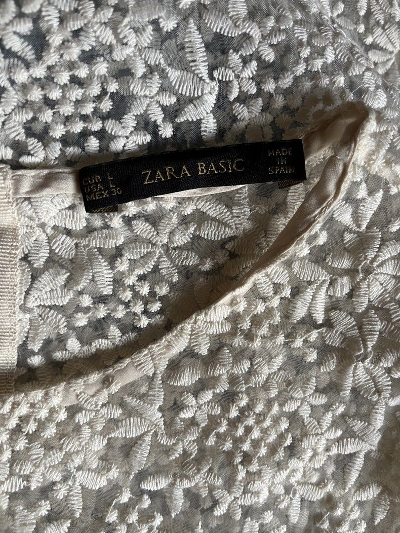 Zara Basic Embroidered Lace Short Sleeve Blouse Size L (Category: Blouses) located in Tandag. Submitted by maryarlale42144 (Listing ID 1467368461, Image 3). Description: - Brand: Zara Basic - Color: White - Material: Sheer mesh with intricate floral embroidery - Design: Short sleeves and round neckline - Origin: Made in Spain - Size: EUR L, USA L, MEX 30 - Condition: Excellent pre-loved condition (ready to wear).