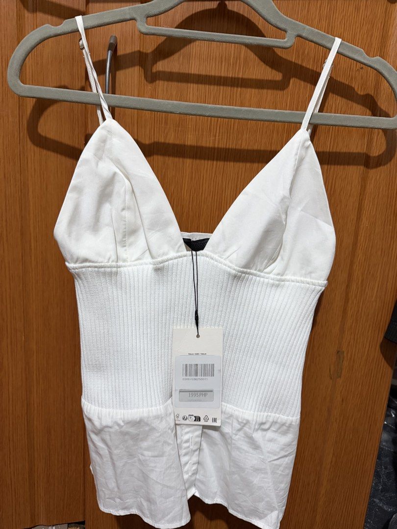 Zara White Cami Ribbed Top (Category: Sleeveless) located in Muntinlupa City. Submitted by biancaagbscloset (Listing ID 1467513244, Image 1). Description: - Brand: Zara - Condition: Brand new with tags attached (Original Price: 1995 PHP) - Color: White - Style: V-neckline with fitted ribbed bodice and adjustable spaghetti straps - Material: Lightweight and breathable - Versatility: Perfect for layering or wearing on hot days - Never worn.