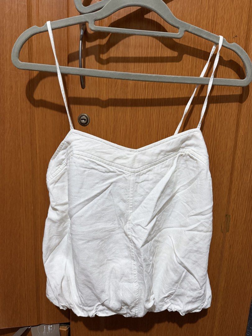 Zara White Spaghetti Strap Cami Crop Top (Category: Sleeveless) located in Muntinlupa City. Submitted by biancaagbscloset (Listing ID 1467514361, Image 1). Description: - Color: White - Style: Camisole top with thin spaghetti straps - Neckline: Sweetheart neck with subtle front seam details - Back Design: Open back with a stretchy elastic band and adjustable side tie strings - Hem: Gathered, slightly bubbled look - Material: Lightweight fabric, i