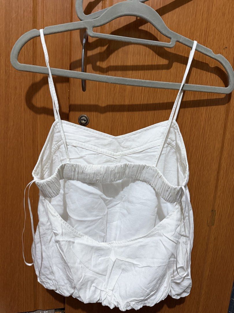 Zara White Spaghetti Strap Cami Crop Top (Category: Sleeveless) located in Muntinlupa City. Submitted by biancaagbscloset (Listing ID 1467514361, Image 2). Description: - Color: White - Style: Camisole top with thin spaghetti straps - Neckline: Sweetheart neck with subtle front seam details - Back Design: Open back with a stretchy elastic band and adjustable side tie strings - Hem: Gathered, slightly bubbled look - Material: Lightweight fabric, i