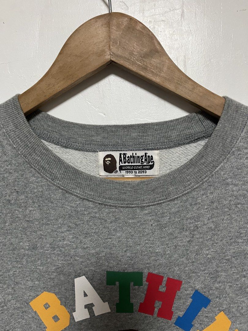 A Bathing Ape Grey Multi-Color Logo Sweatshirt (Category: Coats, Jackets and Outerwear) located in Tanza. Submitted by feliciano4108 (Listing ID 1467798434, Image 3). Description: - Brand: A Bathing Ape (BAPE) - Color: Grey with multi-color striped ribbing (red, green, yellow, black, blue) - Design: Colorful lettering graphic and iconic ape head logo on chest - Condition: Excellent, includes original neck tag and gold ape head wash tag - Authenti