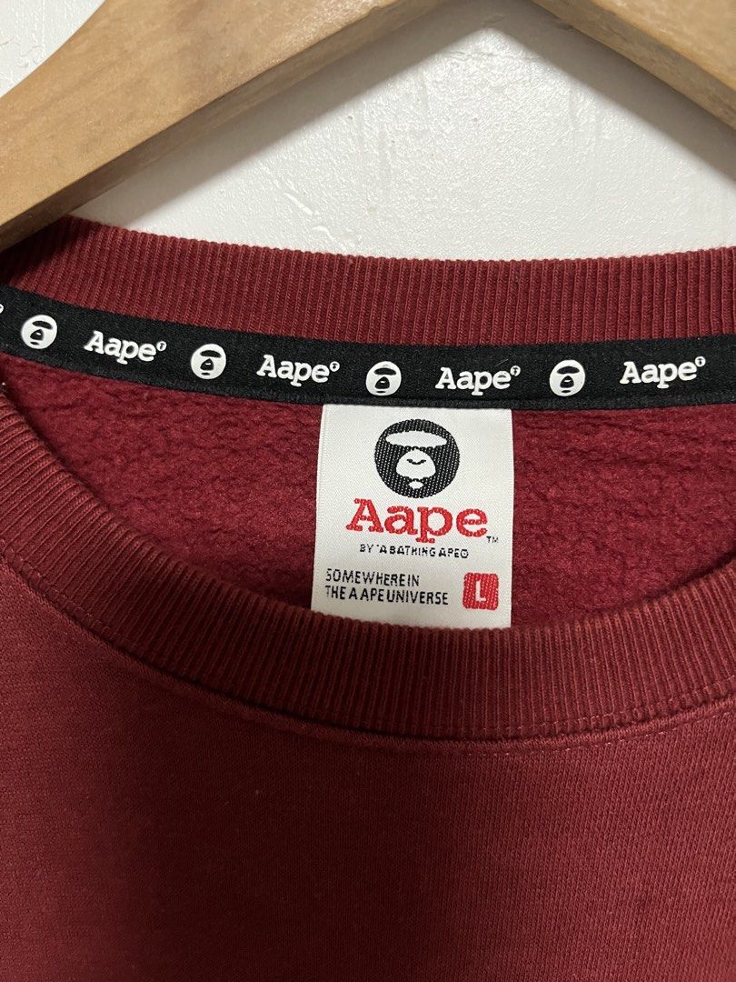 Aape By A Bathing Ape Maroon Sweatshirt (Category: Coats, Jackets and Outerwear) located in Tanza. Submitted by feliciano4108 (Listing ID 1467798322, Image 3). Description: Maroon sweatshirt from Aape by A Bathing Ape. Large Ape Universe graphic printed on the chest. Ribbed cuffs and hem with embroidered branding details on the sleeves. Interior neck tape and woven label tags attached. Size large, relaxed fit. Warm fleece lining inside..