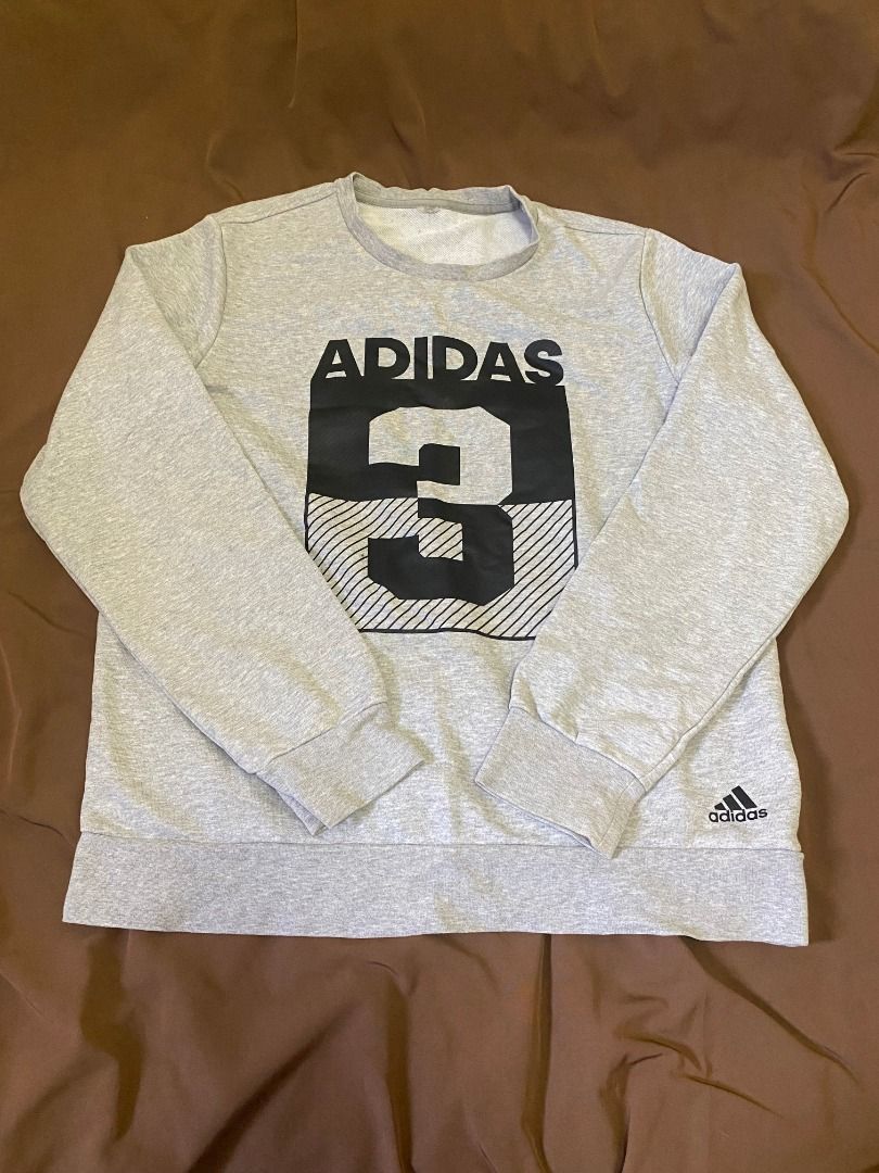Adidas Grey Graphic Sweatshirt (Category: Coats, Jackets and Outerwear) located in San Pablo. Submitted by kisha_santonia (Listing ID 1467666343, Image 1). Description: - Authentic grey Adidas crewneck sweatshirt - Bold chest graphic featuring 'ADIDAS' and large number 3 in a block pattern - Small Adidas logo printed near the bottom hem - Comfortable fleece lining for extra warmth - Classic ribbed cuffs, collar, and hem - Ideal for casual, everyd