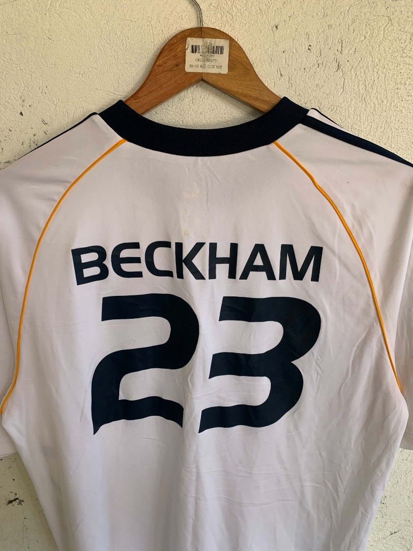 Adidas LA Galaxy Beckham 23 Jersey (Category: Activewear) located in Manila. Submitted by louiseluch69680 (Listing ID 1467654652, Image 3). Description: - Item: LA Galaxy Home Jersey - Player: David Beckham #23 - Color: White with navy blue stripes and yellow piping - Features: Bold vertical 'GALAXY' lettering on the front, Adidas logo, and team crest - Details: Dark blue ribbed collar and cuffs; inner tag shows natural fading from wash and wear 
