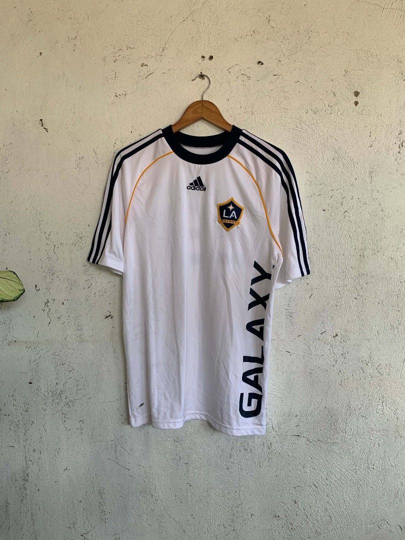 Adidas LA Galaxy Beckham 23 Jersey (Category: Activewear) located in Manila. Submitted by louiseluch69680 (Listing ID 1467654652, Image 1). Description: - Item: LA Galaxy Home Jersey - Player: David Beckham #23 - Color: White with navy blue stripes and yellow piping - Features: Bold vertical 'GALAXY' lettering on the front, Adidas logo, and team crest - Details: Dark blue ribbed collar and cuffs; inner tag shows natural fading from wash and wear 