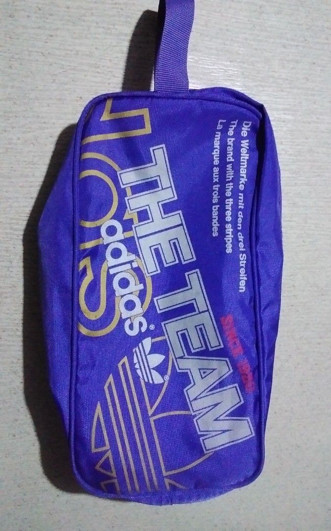 Adidas shoe bags (Category: Announcements) located in Quezon City. Submitted by Bernz (Listing ID 1467723857, Image 1). Description: This is a vintage Adidas Originals shoe bag (or boot bag) featuring a retro "The Team" design. Key Features Design Elements: It displays the classic Trefoil logo, the slogan "Die Weltmarke mit den drei Streifen" (The brand with the three stripes), and text reading "THE TEAM" running vertically along the front.Functi