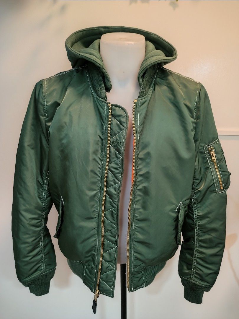 Alpha Industries Green Hooded Bomber Jacket (Category: Coats, Jackets and Outerwear) located in La Trinidad. Submitted by padasem_kadi (Listing ID 1467641646, Image 1). Description: - Brand: Alpha Industries - Color: Sage green with signature bright orange lining - Features: Attached green hood, gold-toned metal zippers, and utility pocket on left sleeve - Details: Quilted inner placket with embroidered logo and contrast white stitching - Fit & C
