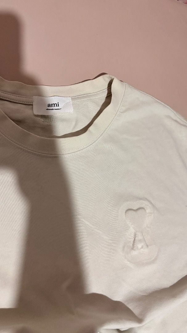Ami Paris T-Shirt Off White Embossed Logo (Category: Tshirts & Polo Shirts ) located in Molave. Submitted by shoethriftengs (Listing ID 1467701954, Image 1). Description: - Brand: Ami Paris - Color: Off-white - Material: 100% comfortable cotton - Design: Embossed logo on front chest with small embroidered Ami lettering near the back neckline - Fit: Classic crew neck and short sleeves - Condition: Excellent, comes with original inside branding and
