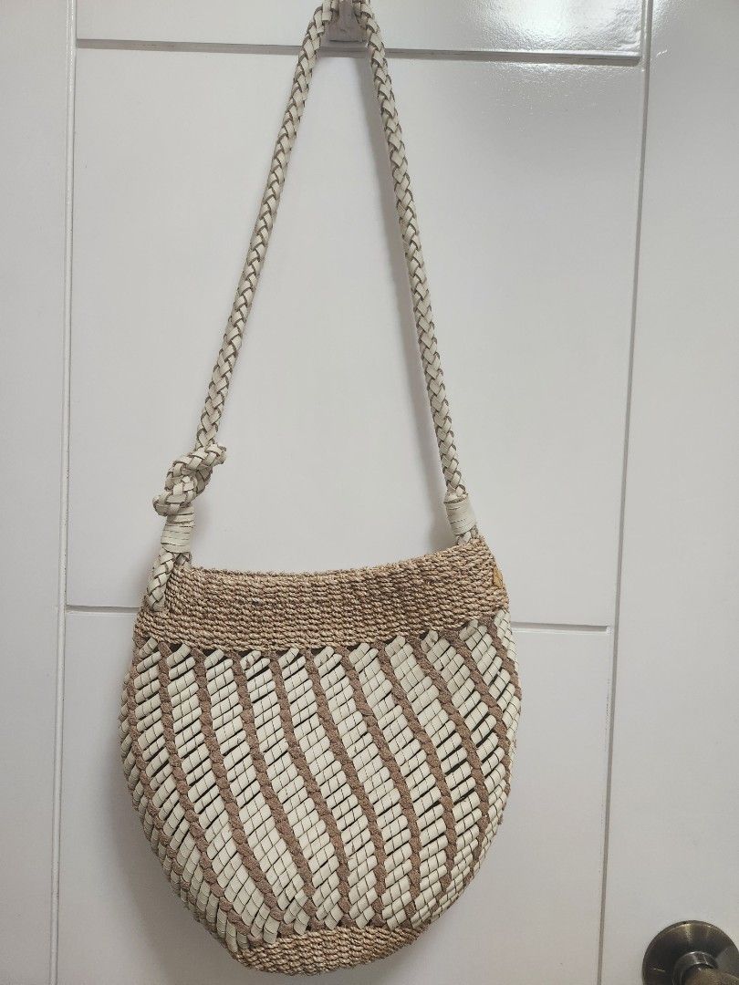 Aranaz Joy Bucket Bag (Category: Shoulder Bags) located in Makati City. Submitted by mikamix (Listing ID 1467604320, Image 2). Description: - Brand: Aranaz - Style: Joy Bucket Bag - Origin: Handcrafted in the Philippines - Material: Woven straw and premium leather - Color: Neutral beige and white - Details: Braided shoulder strap with decorative knot, drawstring fabric lining, and metal brand logo plaque - Condition: Excellent - Perfect for: Casu