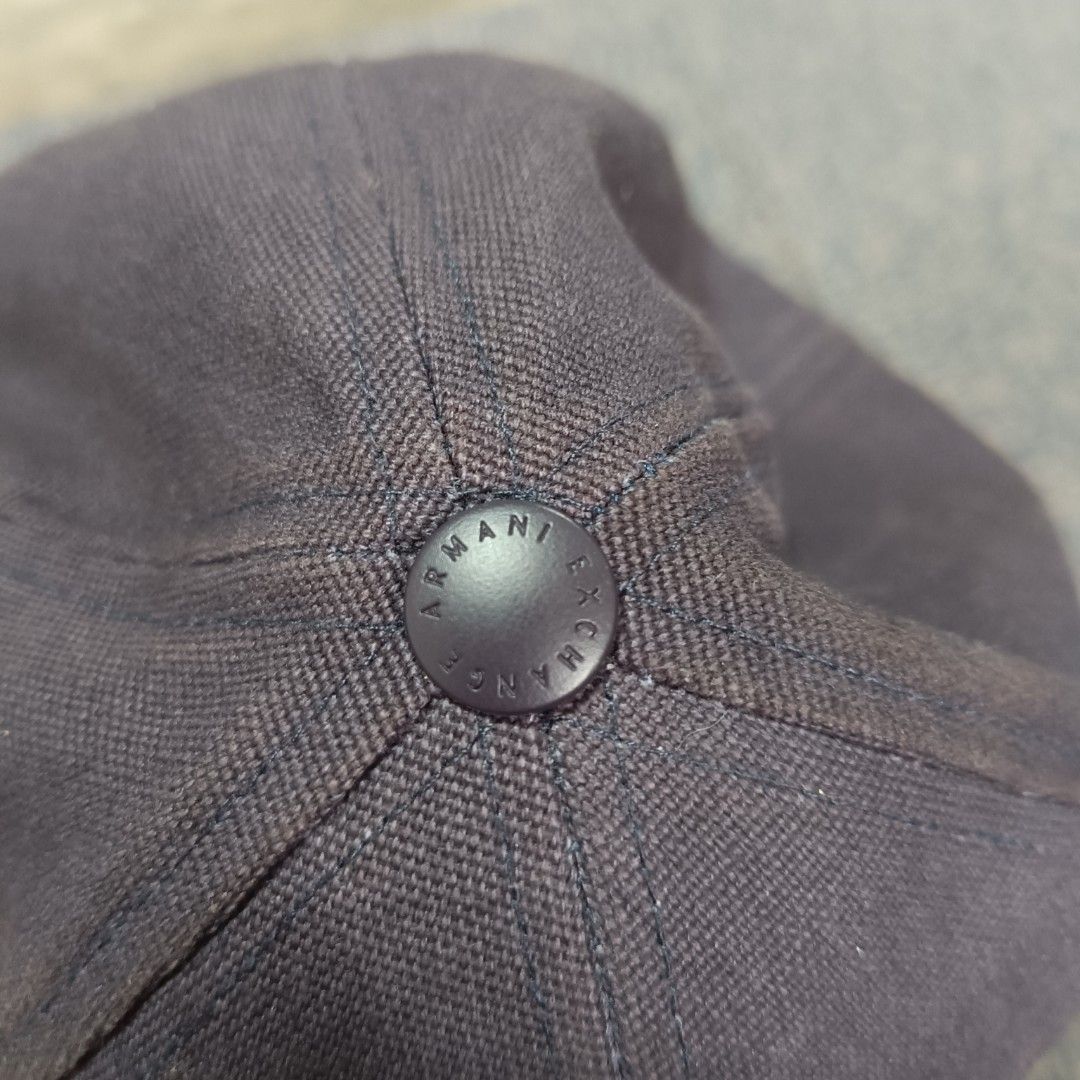 Armani Exchange (Category: Caps & Hats) located in Angeles City. Submitted by thriftilious.ph (Listing ID 1467647278, Image 3). Description: Armani Exchange baseball cap. Dark grey canvas crown paired with a blue faux leather brim and front patch. Embossed A|X logo on the front patch, button top, and back strap. Adjustable blue strap with metal buckle closure. Interior brand label sewn along the sweatband. Clean and solid construction..