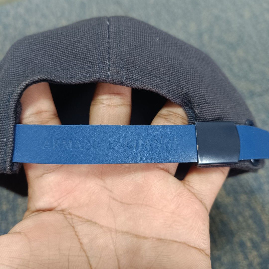 Armani Exchange (Category: Caps & Hats) located in Angeles City. Submitted by thriftilious.ph (Listing ID 1467647278, Image 2). Description: Armani Exchange baseball cap. Dark grey canvas crown paired with a blue faux leather brim and front patch. Embossed A|X logo on the front patch, button top, and back strap. Adjustable blue strap with metal buckle closure. Interior brand label sewn along the sweatband. Clean and solid construction..
