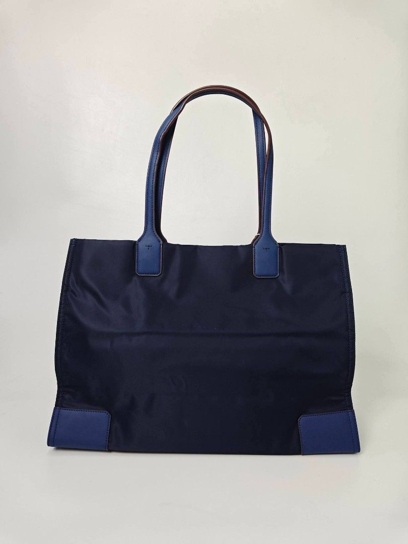Authentic Tory Burch Ella Nylon Tote Bag Blue (Category: Tote Bags) located in Quezon City. Submitted by hollowwillow (Listing ID 1467616203, Image 3). Description: - Authentic Tory Burch Ella tote in classic Navy Blue - Brand new - Lightweight, durable nylon material with matching handles and bottom corner patches - Features iconic large circular logo stamped on the front - Roomy fabric-lined interior equipped with a secure zip pocket and slip c