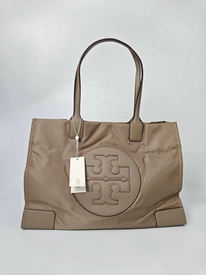 Authentic Tory Burch Ella Tote Bag Taupe (Category: Tote Bags) located in Quezon City. Submitted by hollowwillow (Listing ID 1467616376, Image 1). Description: - Brand: Tory Burch - Condition: Brand new with original store tags - Color: Taupe nylon with matching tan leather trim - Design: Open top with large embossed logo on the front - Straps: Double top handles - Interior: Spacious with 1 zip pocket and 1 slip pocket.