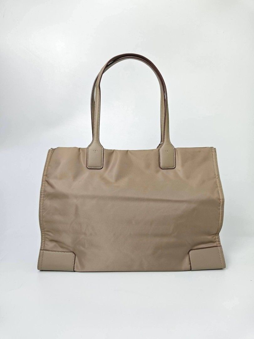 Authentic Tory Burch Ella Tote Bag Taupe (Category: Tote Bags) located in Quezon City. Submitted by hollowwillow (Listing ID 1467616376, Image 3). Description: - Brand: Tory Burch - Condition: Brand new with original store tags - Color: Taupe nylon with matching tan leather trim - Design: Open top with large embossed logo on the front - Straps: Double top handles - Interior: Spacious with 1 zip pocket and 1 slip pocket.