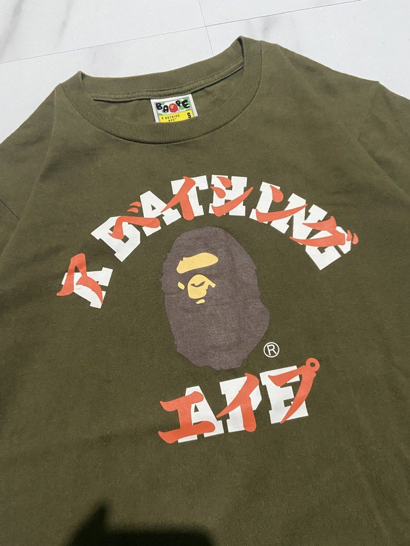 BAPE A Bathing Ape Green Graphic Tee Size S (Category: Tshirts & Polo Shirts ) located in Quezon City. Submitted by johncen (Listing ID 1467725876, Image 2). Description: - Brand: BAPE - Color: Olive green - Size: Small (collar tag verified) - Design: Classic ape head graphic with bold white and orange text - Details: Embroidered ape patch on the sleeve - Material: Heavyweight cotton - Condition: Clean fabric with crisp, high-quality print.