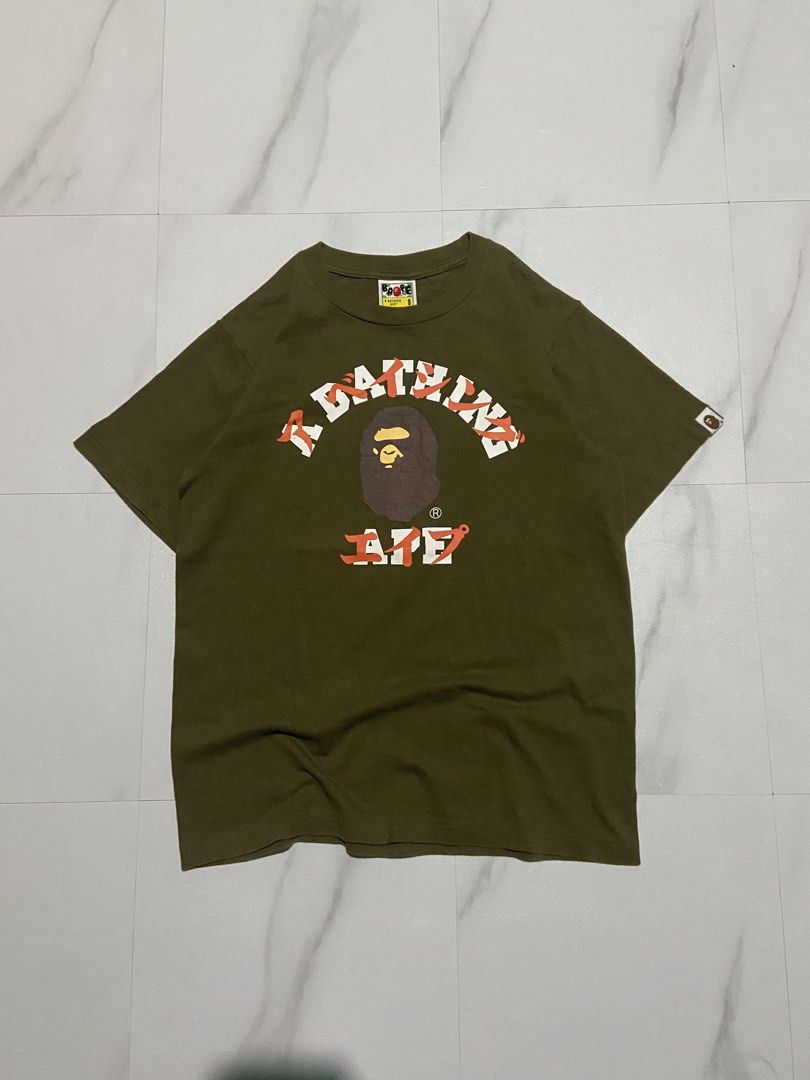 BAPE A Bathing Ape Green Graphic Tee Size S (Category: Tshirts & Polo Shirts ) located in Quezon City. Submitted by johncen (Listing ID 1467725876, Image 1). Description: - Brand: BAPE - Color: Olive green - Size: Small (collar tag verified) - Design: Classic ape head graphic with bold white and orange text - Details: Embroidered ape patch on the sleeve - Material: Heavyweight cotton - Condition: Clean fabric with crisp, high-quality print.