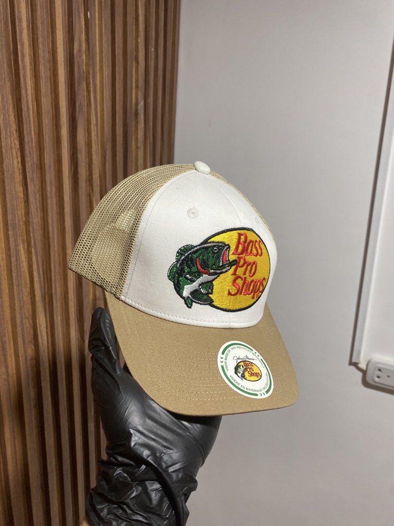 Bass Pro Shops Trucker Hat Beige White (Category: Caps & Hats) located in Caloocan City. Submitted by heatedcaps4425 (Listing ID 1467804059, Image 2). Description: - Authentic Bass Pro Shops trucker hat - Iconic embroidered fish patch on the front - Classic white front crown with khaki beige brim - Breathable mesh back panels with adjustable snapback closure - Includes original Johnny Morris recycled materials visor sticker - Great for outdoor ac