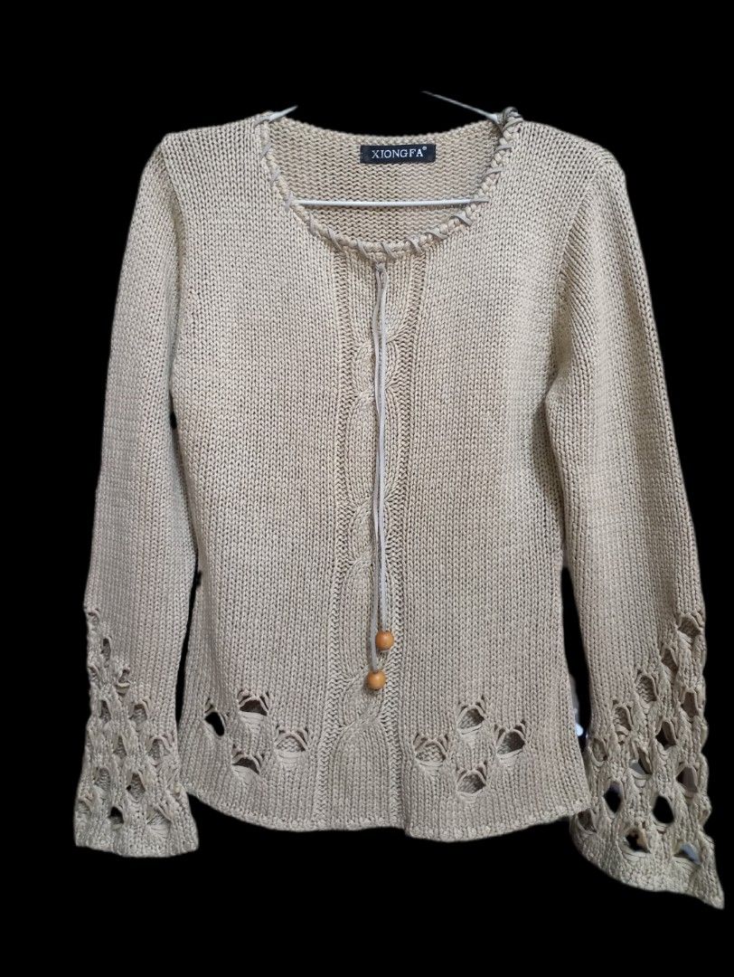 Beige Knitted Sweater (Category: Coats, Jackets and Outerwear) located in General Santos City (Dadiangas). Submitted by silvkimber62755 (Listing ID 1467754884, Image 1). Description: - Brand: Xiongfa - Color: Neutral beige (earth tone) - Style: Long-sleeve knit sweater with soft vertical ribbing - Details: Round neckline with woven leather-look trim and hanging wooden beads - Accents: Cutout lattice patterns along the lower hem and sleeve cuffs -