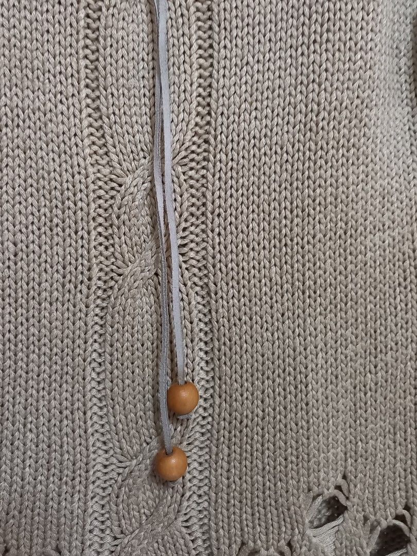 Beige Knitted Sweater (Category: Coats, Jackets and Outerwear) located in General Santos City (Dadiangas). Submitted by silvkimber62755 (Listing ID 1467754884, Image 2). Description: - Brand: Xiongfa - Color: Neutral beige (earth tone) - Style: Long-sleeve knit sweater with soft vertical ribbing - Details: Round neckline with woven leather-look trim and hanging wooden beads - Accents: Cutout lattice patterns along the lower hem and sleeve cuffs -
