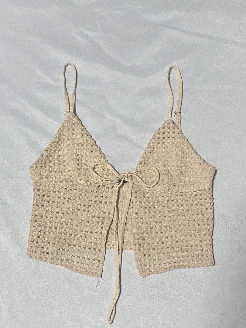 Beige Textured Crop Top with Tie Front (Category: Sleeveless) located in Paranaque City. Submitted by pomeloluvr (Listing ID 1467678308, Image 1). Description: - Color: Beige - Material/Style: Knitted waffle texture, crop top - Features: Adjustable spaghetti straps with metal sliders, cute tie-front ribbon detail - Condition: Great basic piece with slight loose threads near the bottom hem (visible in photos) - Versatility: Perfect for layering or