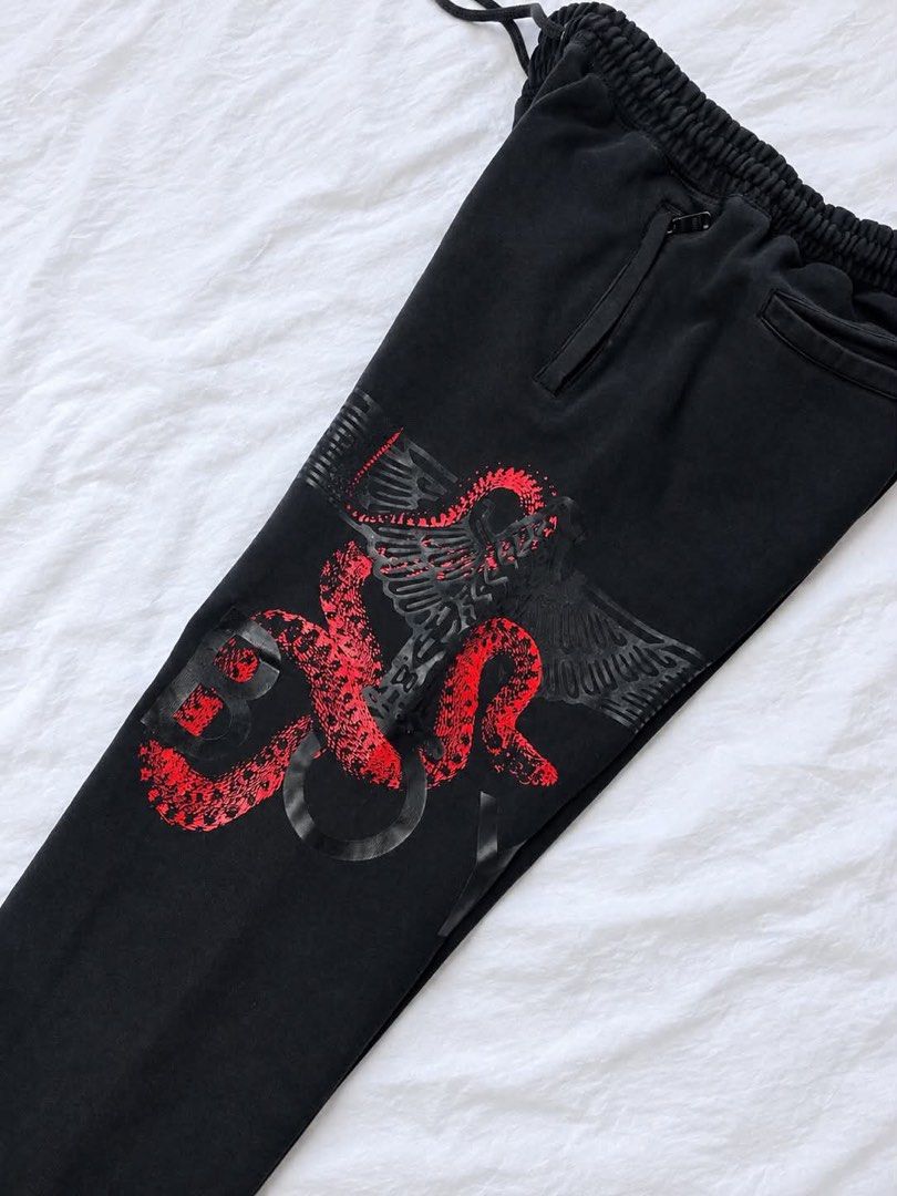 BOY London Joggers Sweatpants Black Red Snake Eagle (Category: Joggers) located in Manila. Submitted by rewornthrifts (Listing ID 1467670204, Image 2). Description: - Brand: BOY London - Color: Black with bold red snake and eagle graphic on the left leg - Material: Comfortable, high-quality cotton-blend fabric - Fit & Comfort: Elastic waistband with adjustable drawstring and ribbed cuffs - Pockets: Secure zippered front pockets and a practical ba