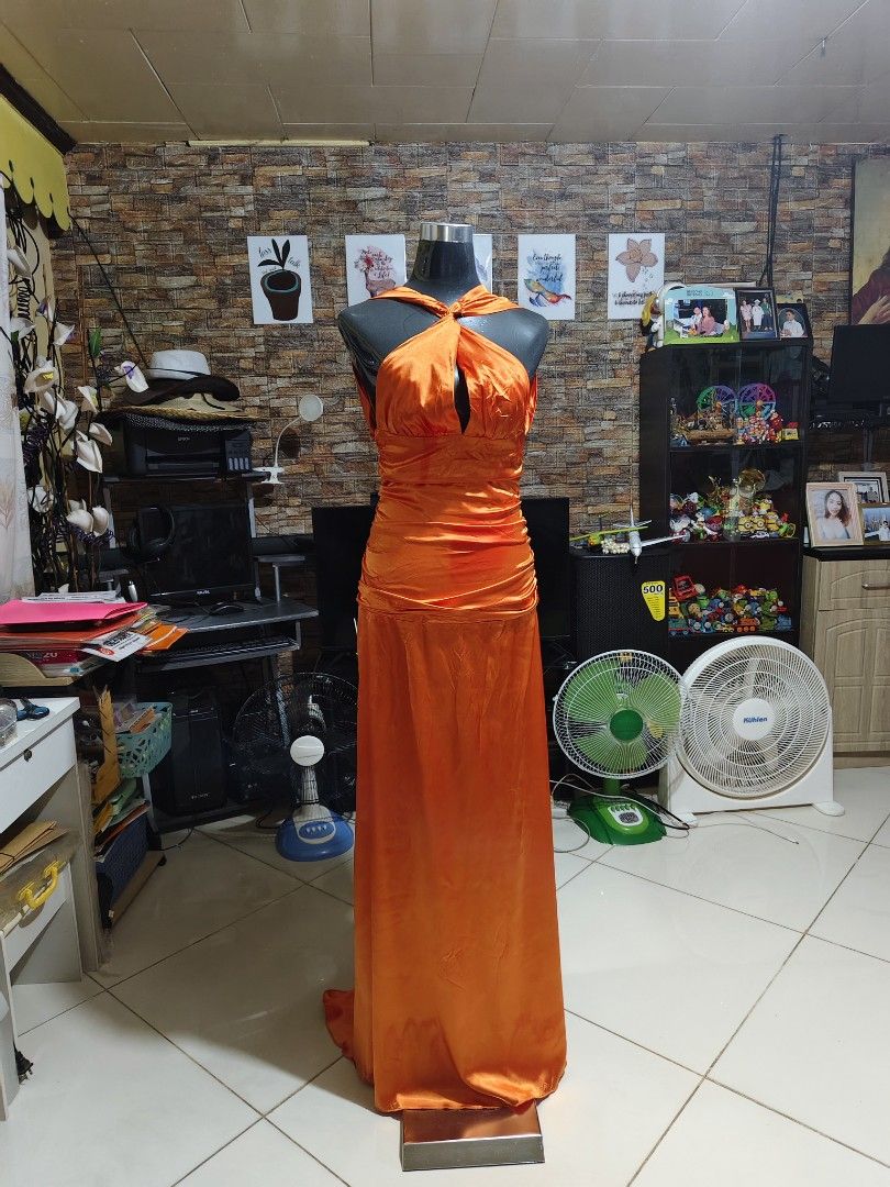Long Orange Halter Gown open back satin fabric (Category: Evening dresses & gowns) located in Manila. Submitted by duffy-080 (Listing ID 1467654364, Image 2). Description: - Color: Vibrant orange - Material: Silky satin - Neckline: Halter with knotted front twist and center keyhole cutout - Waist: Gathered ruching detail - Back Design: Deep open back with concealed lower zipper closure - Length: Full-length maxi skirt pooling slightly at the floo