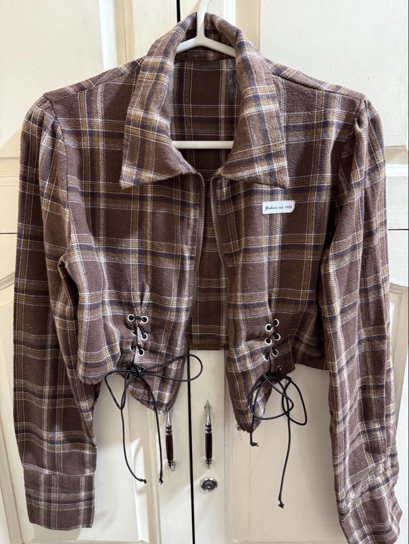 Brown Plaid Cropped Zip Up Jacket (Bought in Korea) (Category: Coats, Jackets and Outerwear) located in Manila. Submitted by secondfinds09 (Listing ID 1467715977, Image 2). Description: - Style: Brown plaid crop jacket with long sleeves and pointed collar - Closure: Front silver zipper - Details: Adjustable lace-up corset on both sides of the waist and a small Yankees est. 1903 white brand label on the left chest - Material: Thick, cozy flannel-l