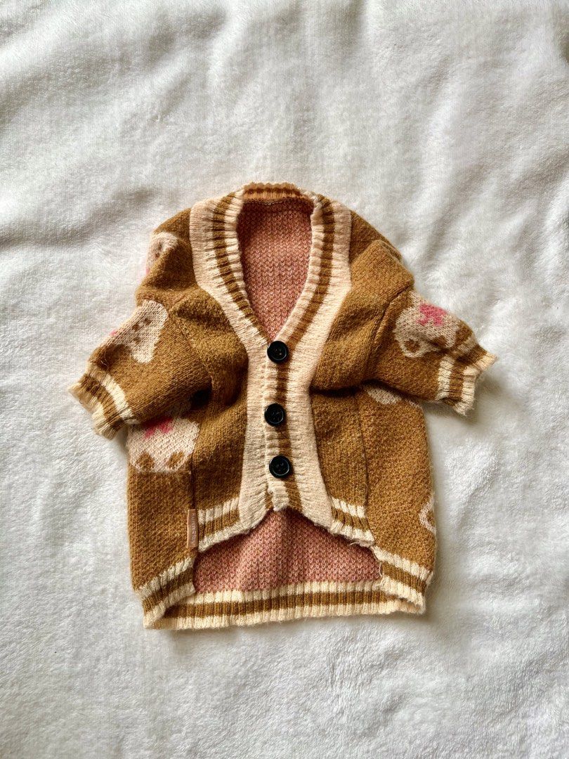 Brown Teddy Bear Pattern Knit Pet Cardigan (Category: Coats, Jackets and Outerwear) located in Taguig. Submitted by call.me.eni (Listing ID 1467318052, Image 1). Description: - Adorable brown knit cardigan for pets with all-over teddy bear pattern and pink bows - Classic V-neck design featuring 3 black front buttons for easy wear - Cream striped ribbing at the collar, cuffs, and hem for a snug fit - Soft pink inner lining for extra comfort and wa