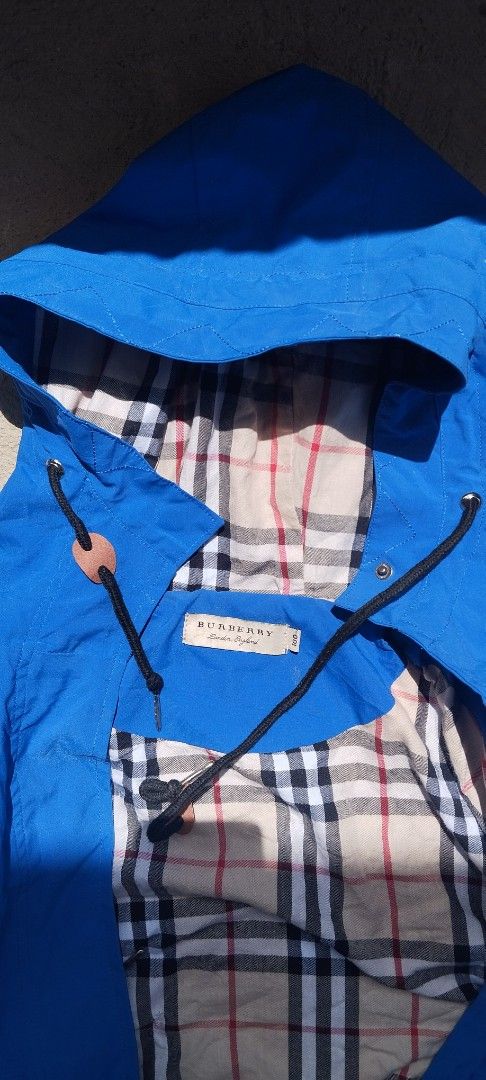 Burberry Blue Hooded Jacket Size small (Category: Coats, Jackets and Outerwear) located in Manila. Submitted by reilly.bee (Listing ID 1467635900, Image 2). Description: - Brand: Burberry - Color: Bright blue with classic Nova check lining - Size: 100 - Features: Front zip and snap button closure, adjustable black drawstrings with leather toggles, deep front pockets - Condition: Clean inside and out, great for cooler weather.