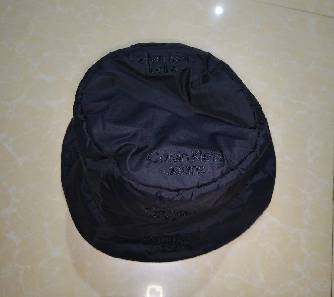 Calvin Klein Jeans Black Bucket Hat (Category: Caps & Hats) located in Manila. Submitted by purefire-477a (Listing ID 1467720942, Image 2). Description: - Brand: Calvin Klein Jeans - Color: Classic Black - Size: Adult One Size (Fits Most) - Material: Lightweight nylon (foldable and packable) - Design: All-over subtle embroidered logo print - Condition: Brand new with tags attached, clean inside and out.