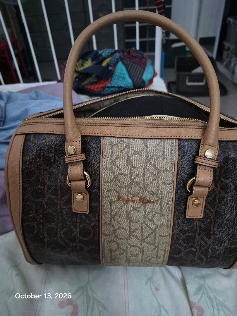 Calvin Klein monogram brown beige satchel handbag (Category: Luxury Bags & Wallets) located in Paranaque City. Submitted by luc522 (Listing ID 1467606718, Image 1). Description: - Brand: Calvin Klein - Style: Monogram satchel / structured barrel shape - Color: Dark brown and beige with tan leather-look trim - Hardware: Gold-tone accents - Closure: Zip top - Handles: Double top handles - Interior: Spacious main compartment for daily essentials - C