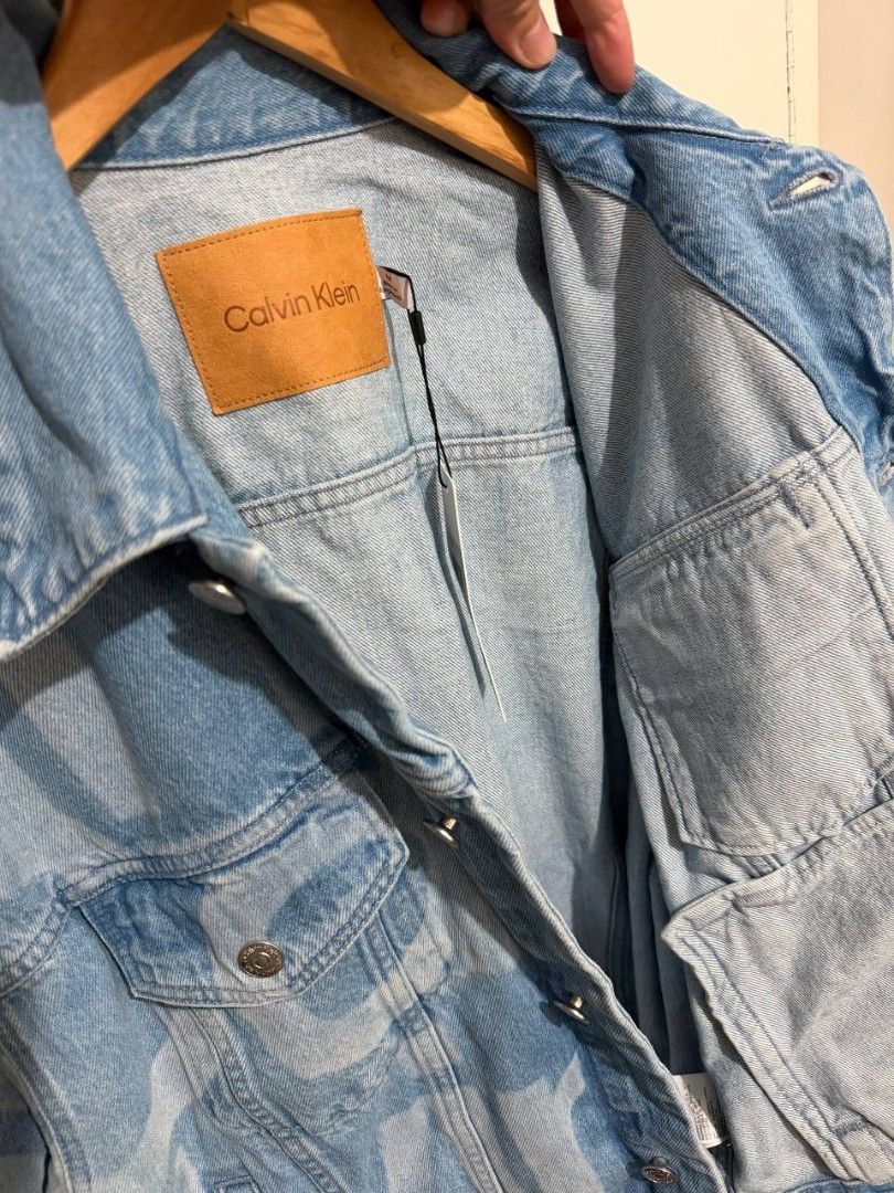Calvin Klein Monogram Denim Jacket (Category: Luxury Apparel) located in Muntinlupa City. Submitted by shopchristianjohn (Listing ID 1467762975, Image 3). Description: Bought online at calvinklein.com. RFS - not my size, jacket is loose fit. Measurements: L: 25" (measured from the collar to the base) W: 25.5" (measured under the armpit) Sleeve lengt: 32" (measured from the collar) Arm opening (arnpit): 12" Cuff 4.5".