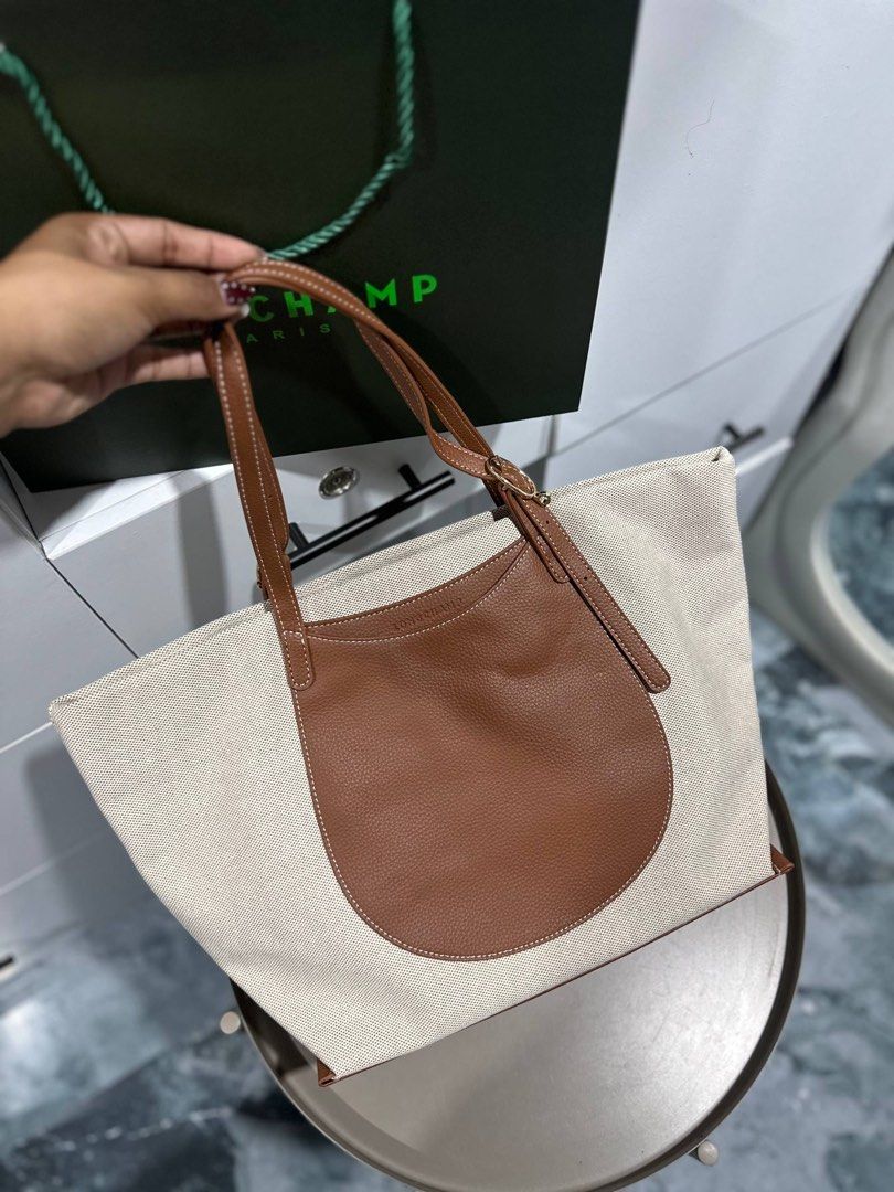 Canvas and Leather Tote Bag Brown (Category: Luxury Bags & Wallets) located in Las Pinas. Submitted by ladyattire (Listing ID 1467638752, Image 3). Description: - Brand: Longchamp - Material: Beige canvas with brown textured leather trim - Straps: Dual shoulder straps with gold-tone buckle hardware and logo branding - Exterior: Front rounded leather pocket with white contrast stitching and debossed Longchamp text - Interior: Spacious fabric-lined