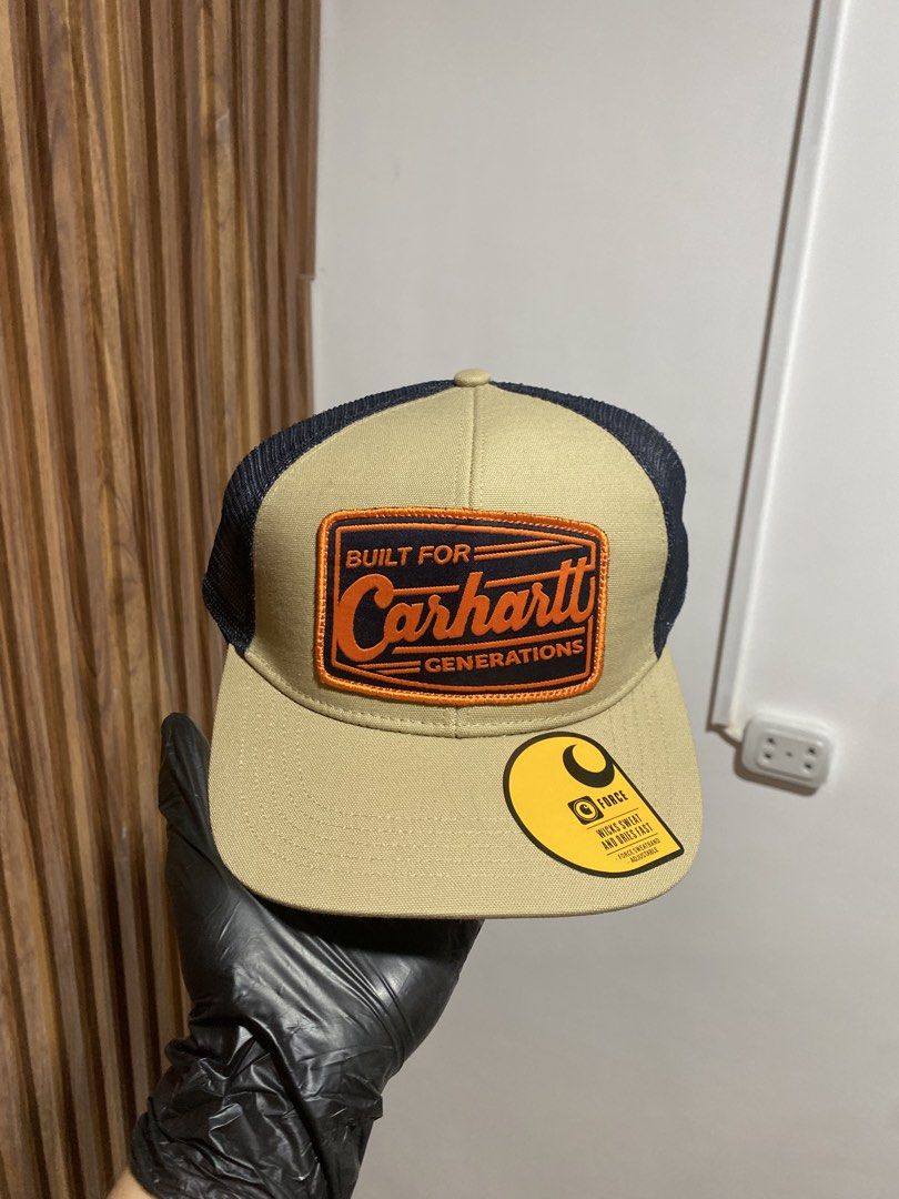 Carinhart AH6928-M Built For Generations Trucker Cap (Category: Caps & Hats) located in Caloocan City. Submitted by heatedcaps4425 (Listing ID 1467803833, Image 1). Description: - Brand: Carhartt (Model: AH6928-M) - Condition: Brand new with tags, never worn - Color: Tan front panels with dark navy mesh back - Design: Orange and navy embroidered 'Built For Generations' patch logo - Brim: Flat brim with original Force sticker attached - Material: 